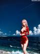 A woman in a red dress standing on a beach.