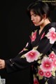 A woman wearing a black kimono with pink flowers on it.