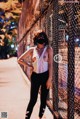 A woman wearing a face mask standing in front of a fence.