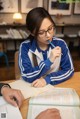 A woman sitting at a table with a pen in her mouth.