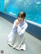 A woman sitting on the floor in front of a large aquarium.