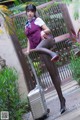 A woman in a purple uniform is posing with a suitcase.