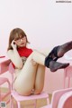 A woman sitting on a pink chair talking on a cell phone.