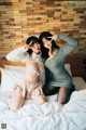 Two young women sitting on a bed posing for a picture.