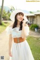 A woman wearing a white dress and a white hat.