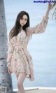 A woman in a pink dress standing next to a palm tree.