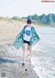 A woman standing on a beach next to the ocean.