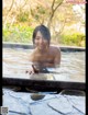 A woman in a hot tub in the middle of a forest.