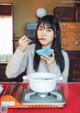 A woman sitting at a table eating a bowl of soup.