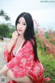 A woman in a red kimono sitting on the ground.