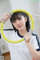 A young woman holding a yellow hula hoop in her hands.